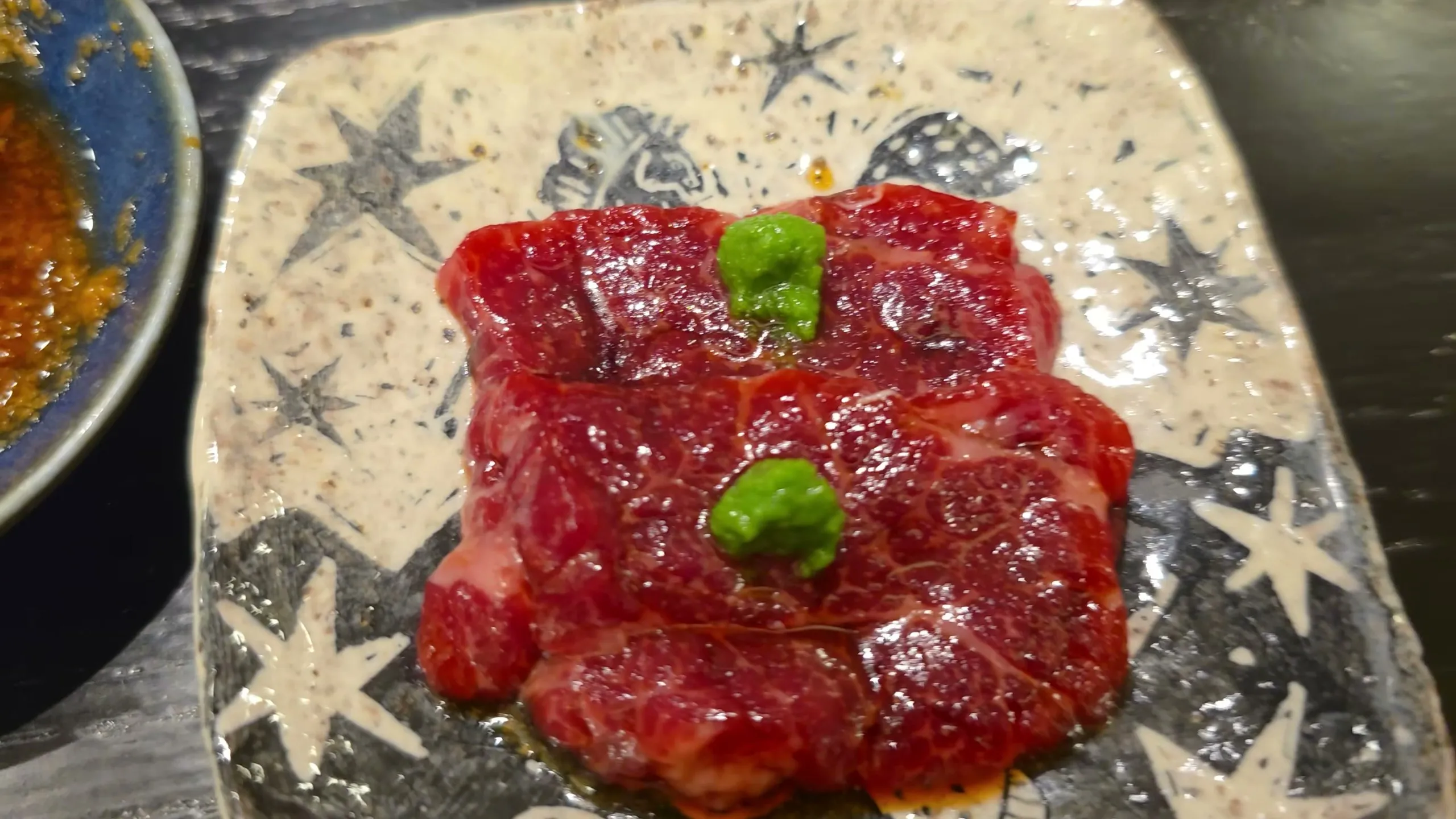 Sliced iwashi kujira whale meat with wasabi on a star-patterned plate